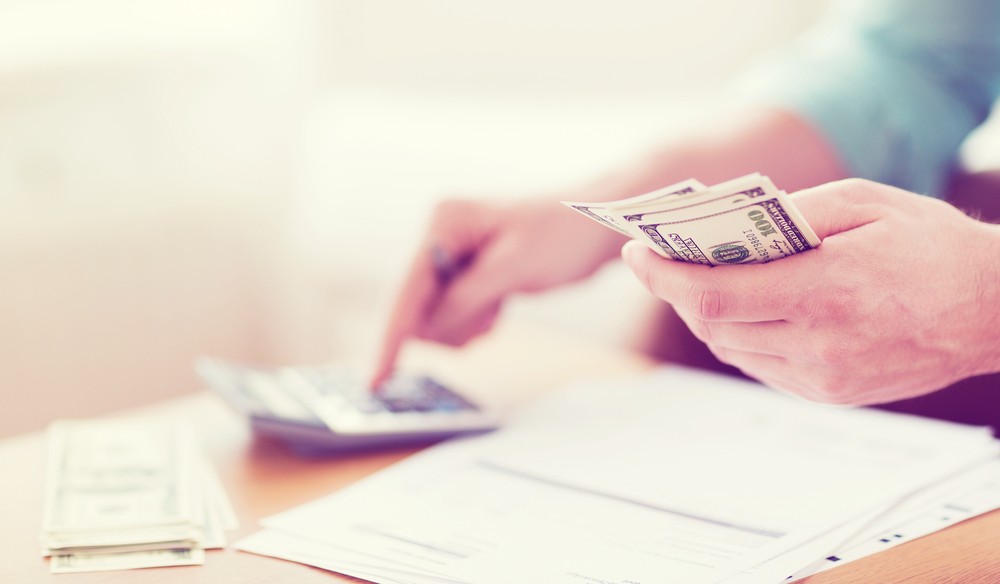 Close up of man with calculator counting money.