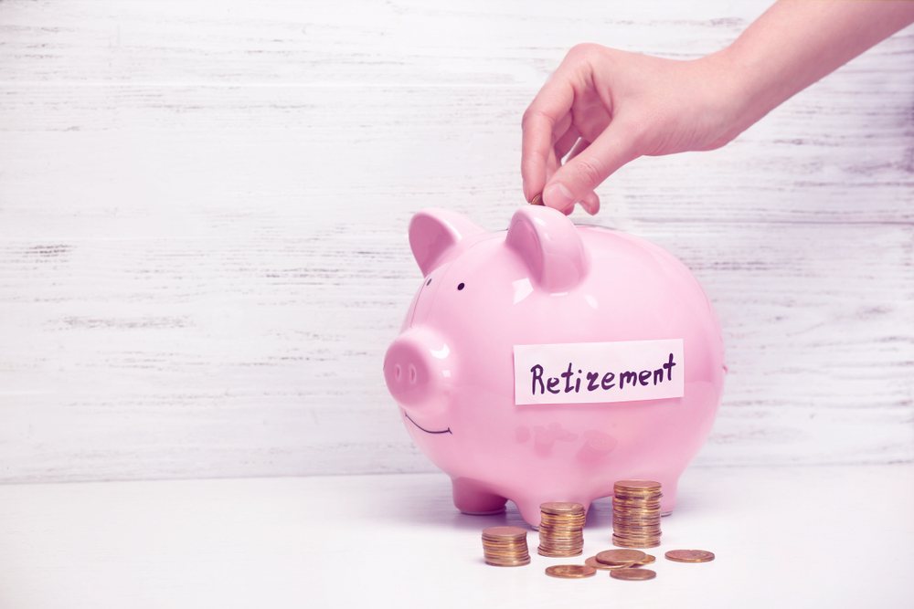 Woman putting coin into piggy bank with label "RETIREMENT". 