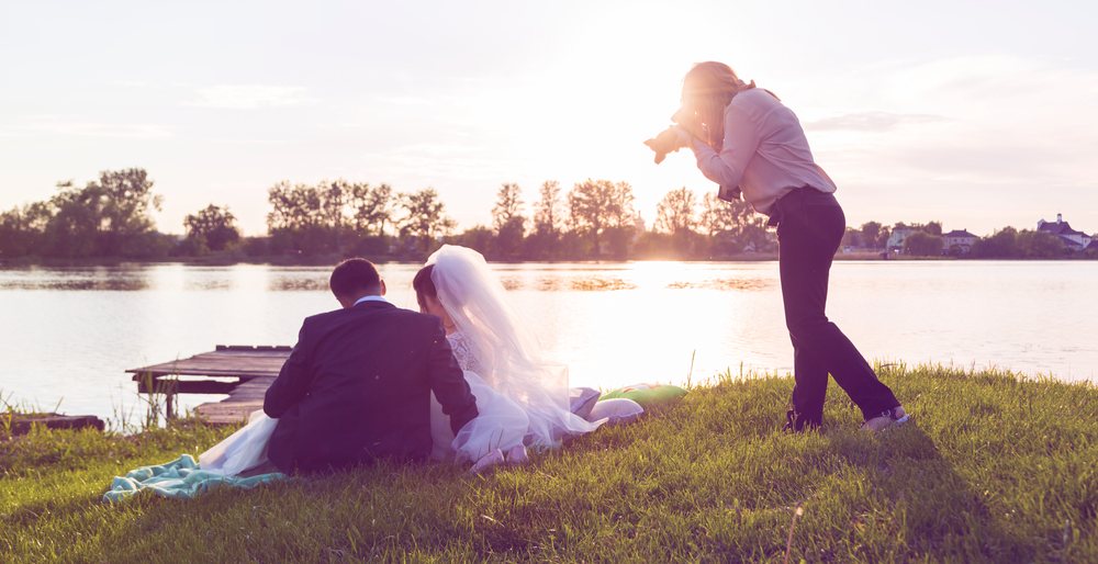 Wedding photographer photographs brides sitting on the lake.