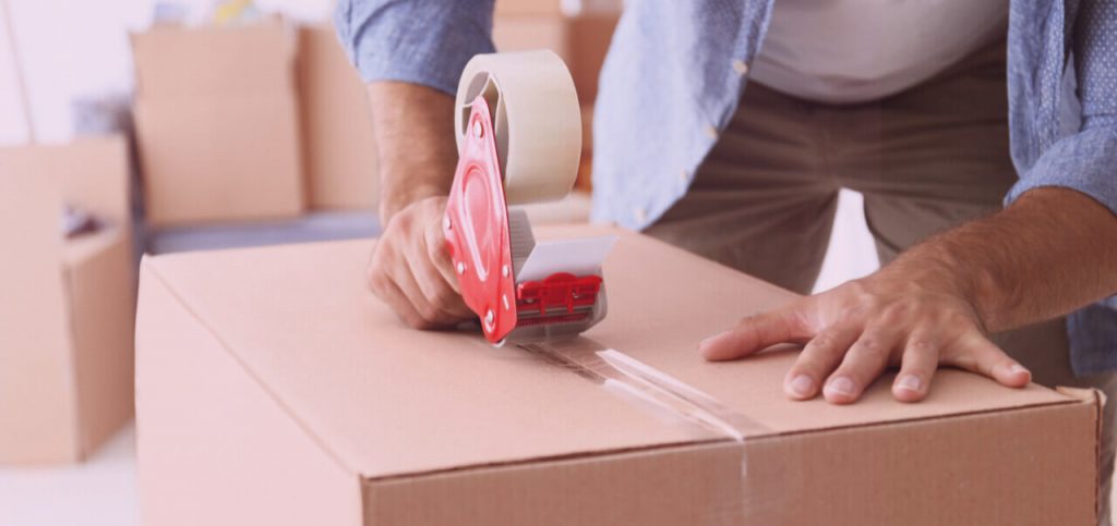  Closeup of man packing cardboard box.