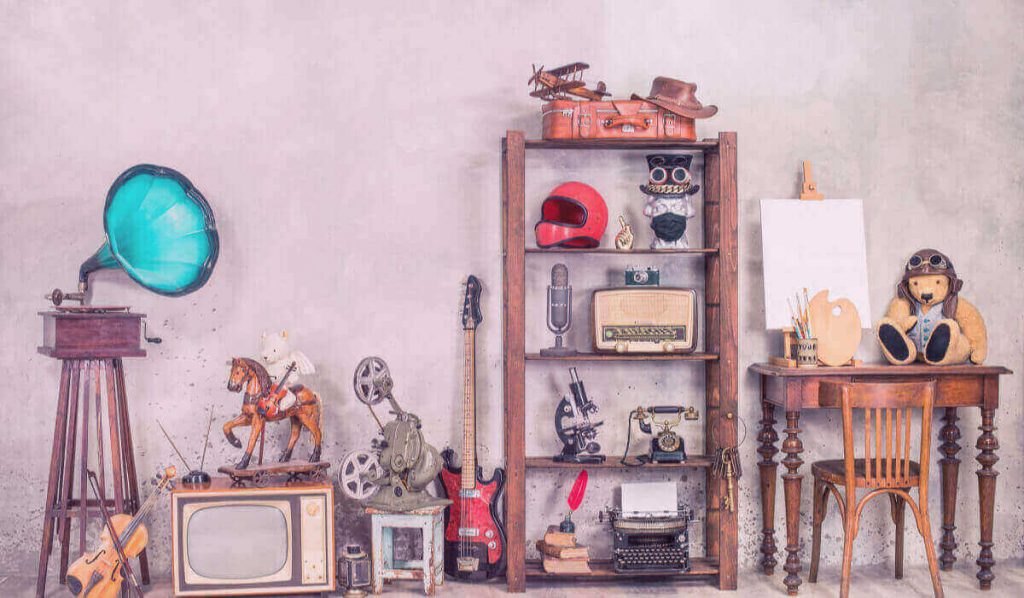 Antique media devices, writers tools, gramophone, film projector, old Teddy Bear toys and white canvas blank on easel, violin and guitar front concrete wall background.