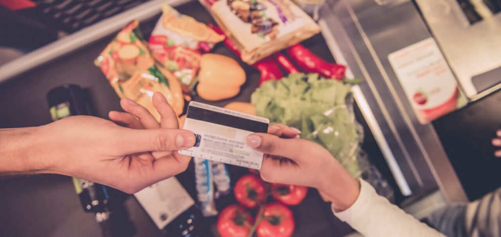 Cropped image of man giving a credit card at the cash desk in the supermarket.