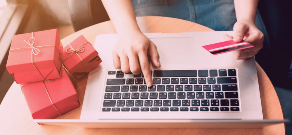 Top view of woman hand holding credit card and doing shopping online near window at home.