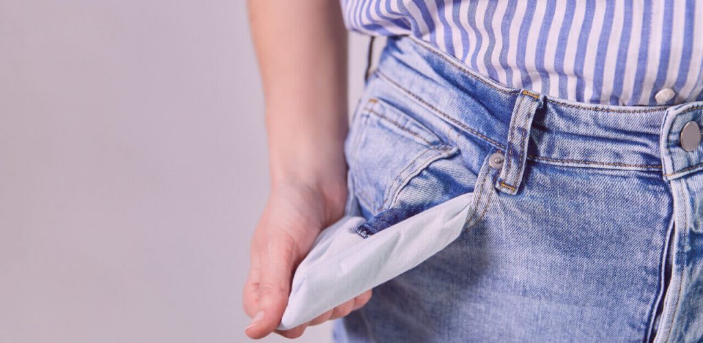 Close up of woman showing empty pockets over gre